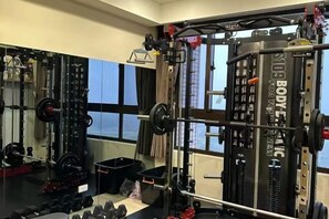 Un gimnasio con equipo de levantamiento de pesas, un espejo y una ventana con vistas.