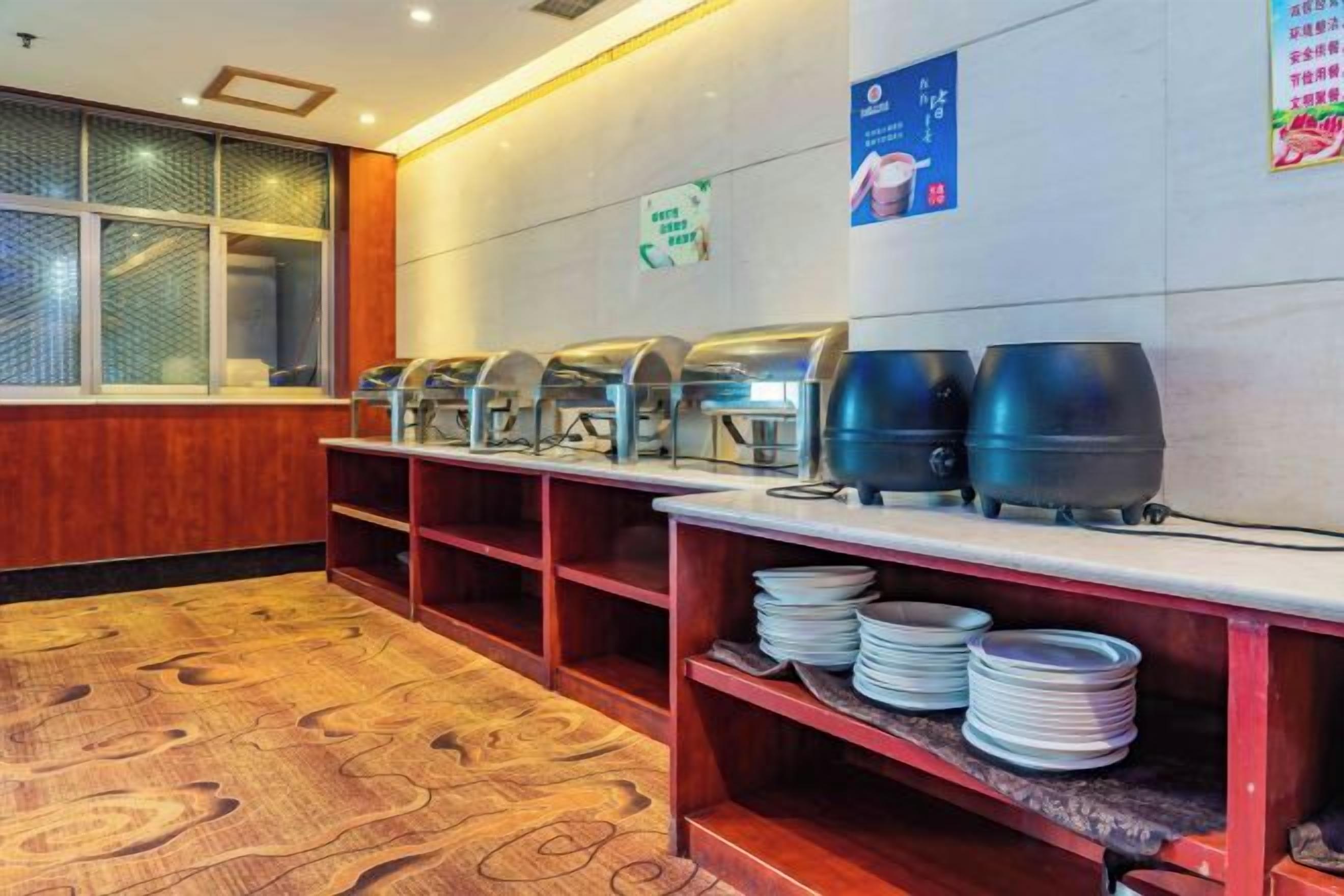 Zona de buffet con varias estaciones de autoservicio, piso de madera y pared con un letrero.
