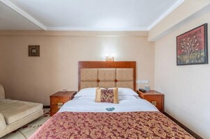 Una habitación de hotel con una cama, una mesita de noche, una silla y un cuadro en la pared.