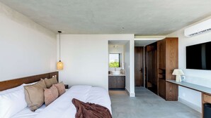 A modern hotel room with a large bed, a bedside lamp, a TV, and a view of the bathroom. - Mojarra 27: New Apt w/Balcony - Heart of Cancun (Cancún)