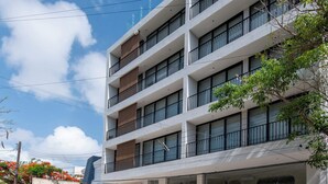 A multi-story building with a modern architectural design, featuring balconies and large windows. - Mojarra 27: New Apt w/Balcony - Heart of Cancun (Cancún)