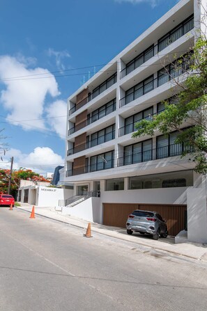 A multi-story building with a modern architectural design, featuring balconies and large windows. - Mojarra 27: New Apt w/Balcony - Heart of Cancun (Cancún)