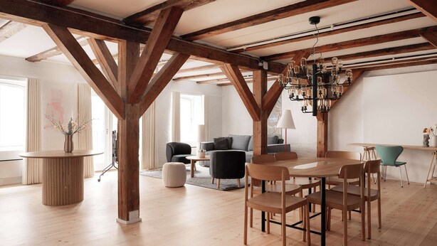 A spacious room with exposed wooden beams, a round wooden table, and modern furniture. - Nyhavn43 Suites 4 by Daniel&Jacob´s (København)