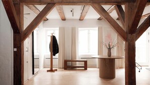 A spacious room with wooden beams, a round table, a bench, and a coat rack. - Nyhavn43 Suites 4 by Daniel&Jacob´s (København)
