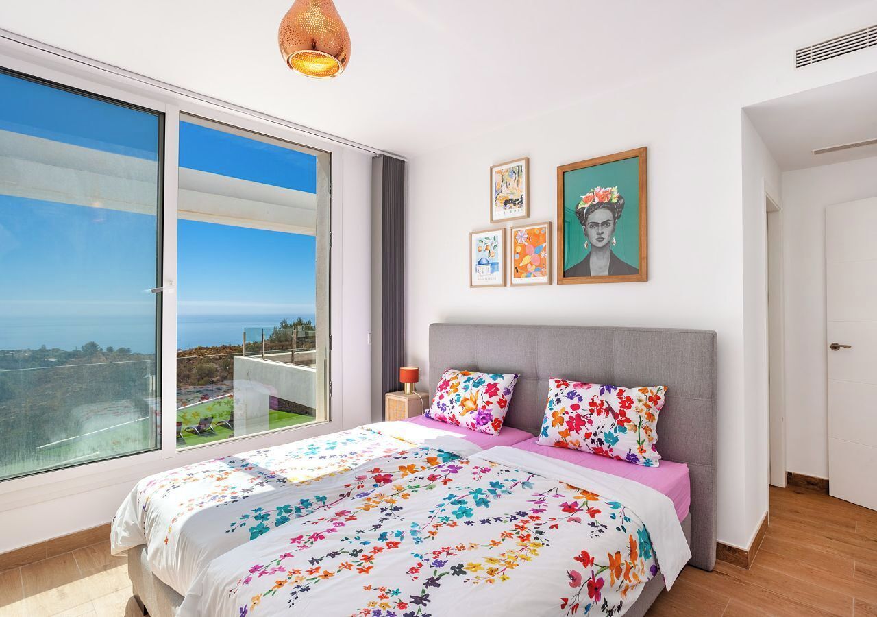 Un dormitorio con una cama grande, vista al mar y obras de arte en la pared.