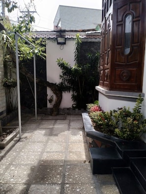 Een binnentuin met betegelde vloer, een houten deur en potplanten.