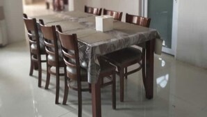 Una sala da pranzo con un tavolo rettangolare, sei sedie e una porta.