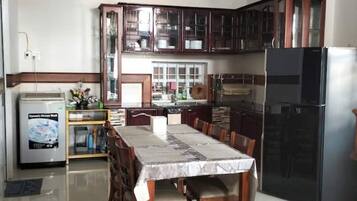 Una cocina moderna con armarios de madera, una mesa de comedor con sillas, un refrigerador y un ventilador de techo.