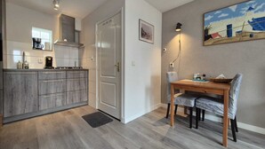 Una cocina moderna con armarios grises, una mesa de comedor con sillas y un cuadro en la pared.