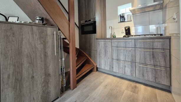 Una cocina moderna con armarios de madera, horno empotrado y campana extractora de acero inoxidable.