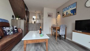 Una sala de estar moderna con un sofá, una mesa de centro, un televisor y un comedor.