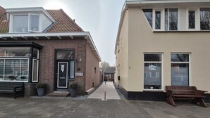 Eine schmale Straße mit einer schwarzen Tür und einem Schild für 'Studio Kenty' an einem Backsteinhaus.