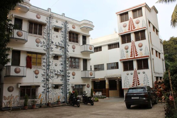 Un hotel de varios pisos con balcones, una zona de estacionamiento y diseños decorativos en la fachada.