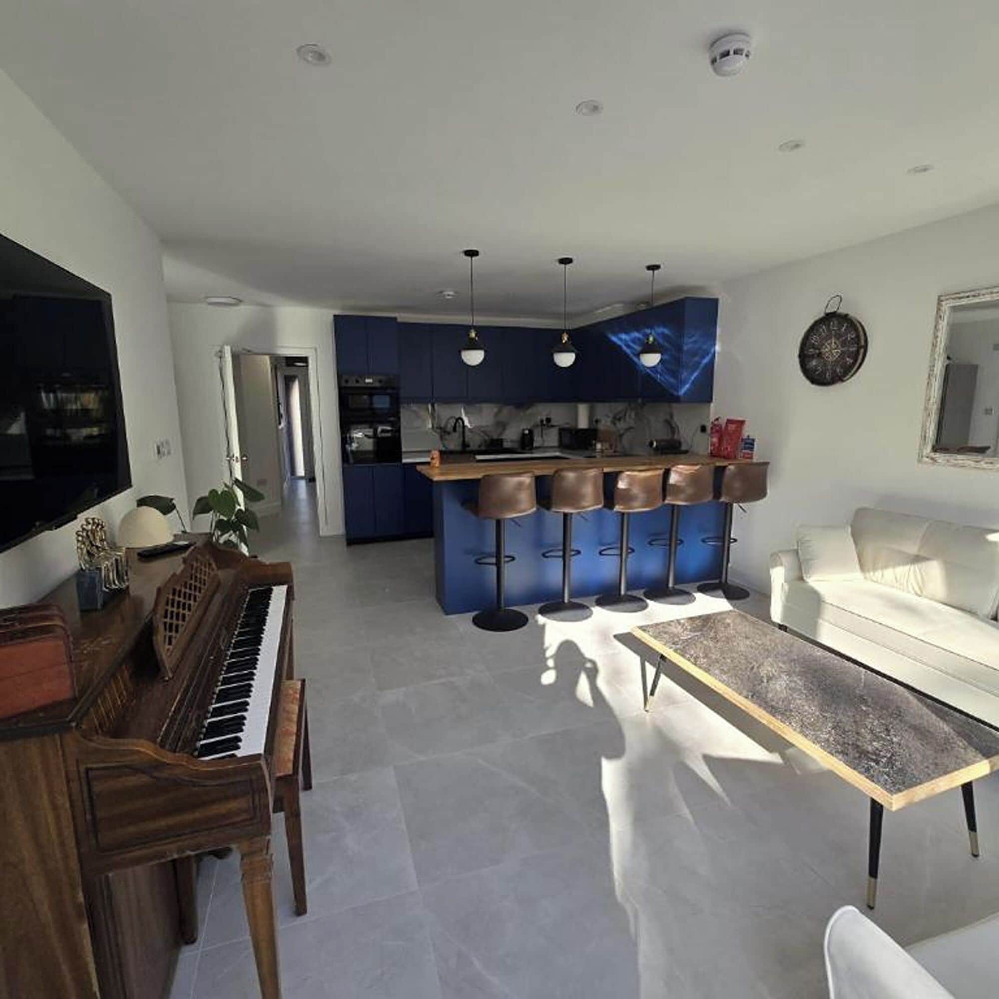Ett modernt vardagsrum med ett piano, en vit soffa och ett soffbord.