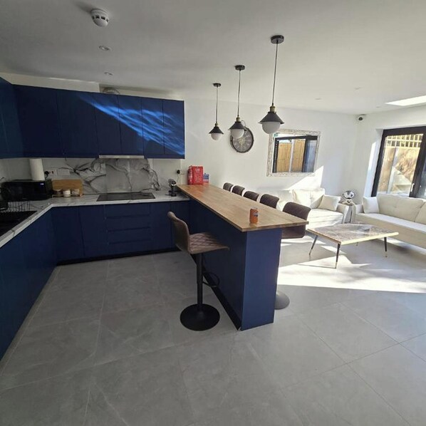 A modern kitchen with blue cabinets, a central island, and pendant lighting.
