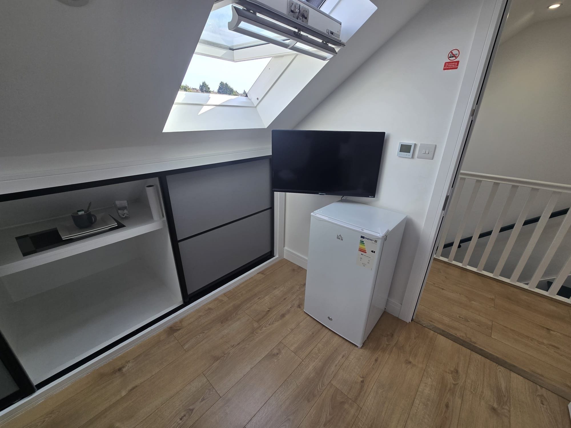 A compact kitchenette with a built-in TV, a small refrigerator, and a skylight.