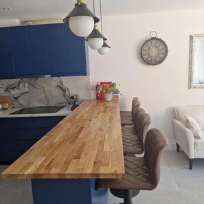 A modern kitchen with blue cabinets, a wooden island, and pendant lighting.