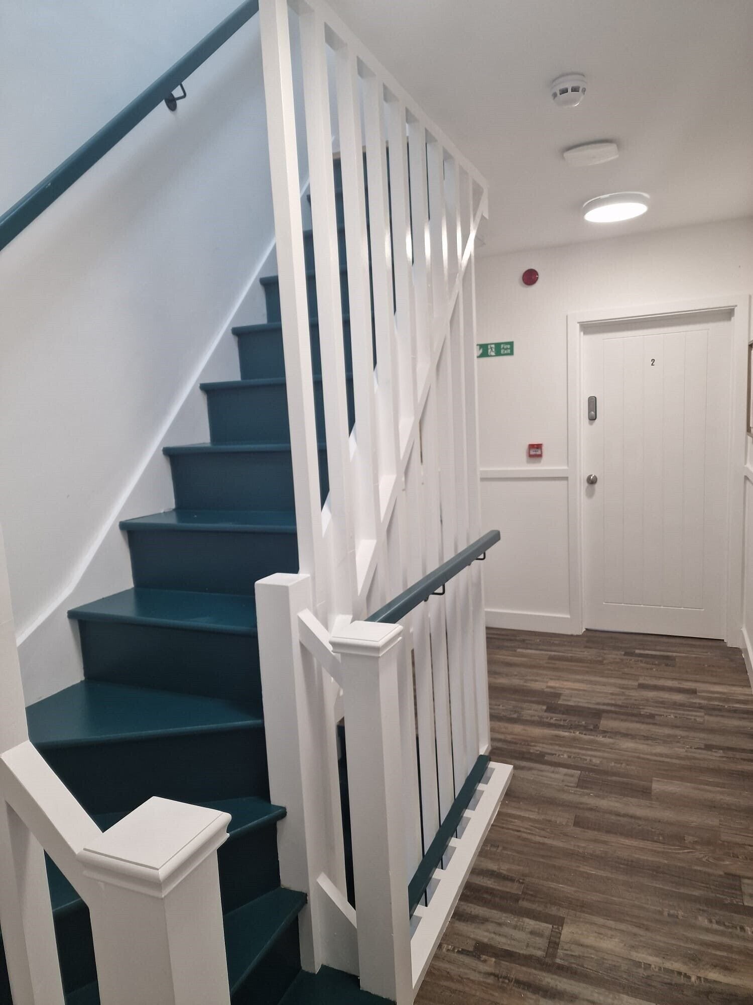 A staircase with white railings and dark steps leading to a door marked with the number 2.
