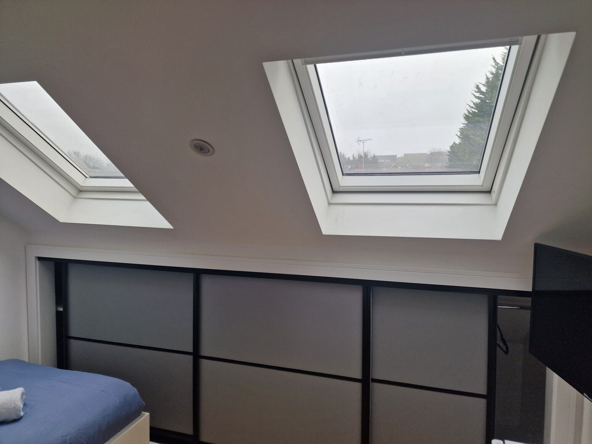A room with a bed, a built-in wardrobe, and skylights.