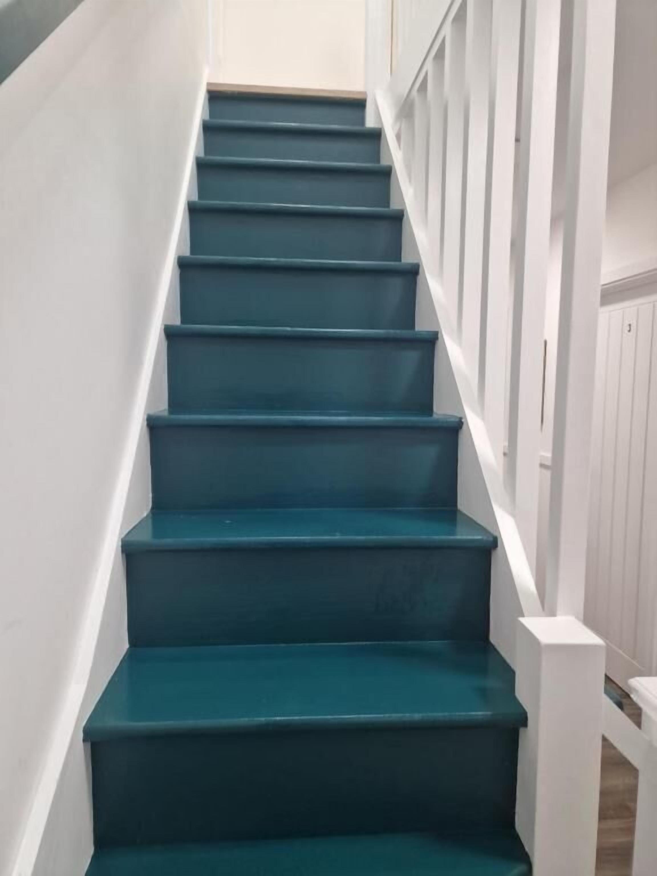 A staircase with teal steps and white railings.