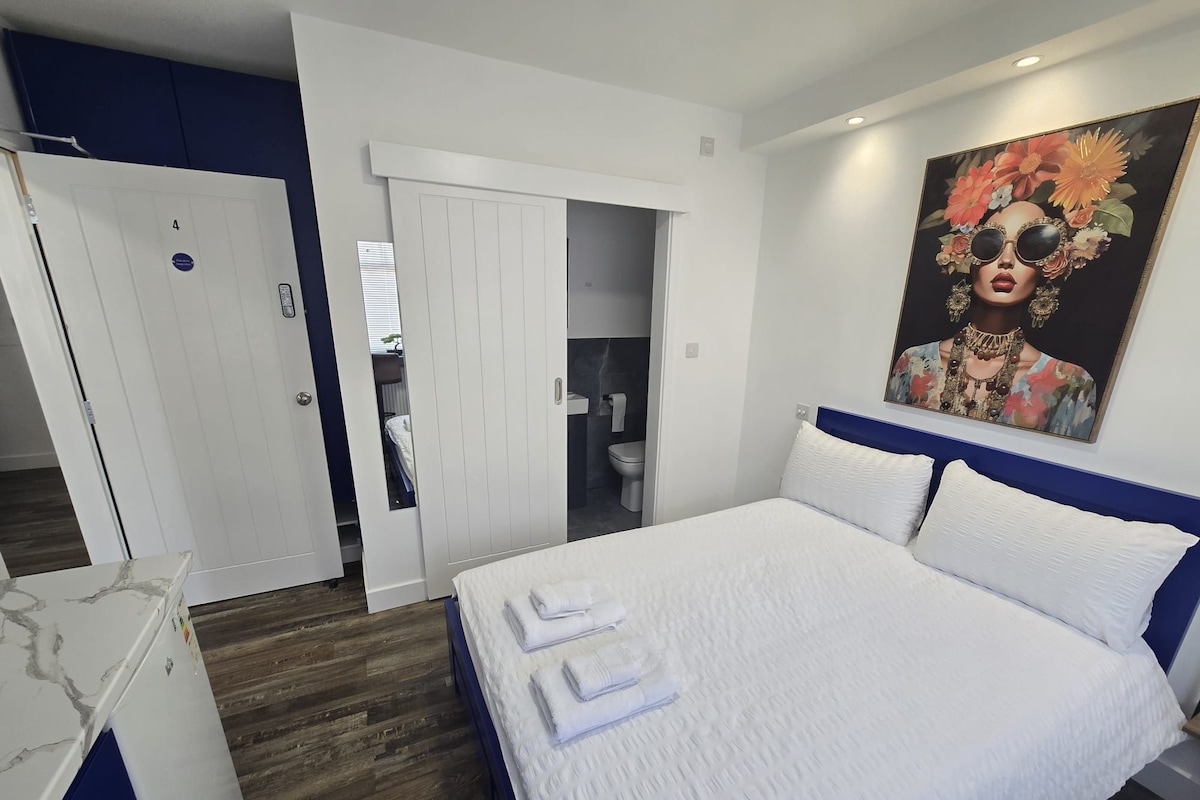 A bedroom with a bed, a wardrobe, and a bathroom.