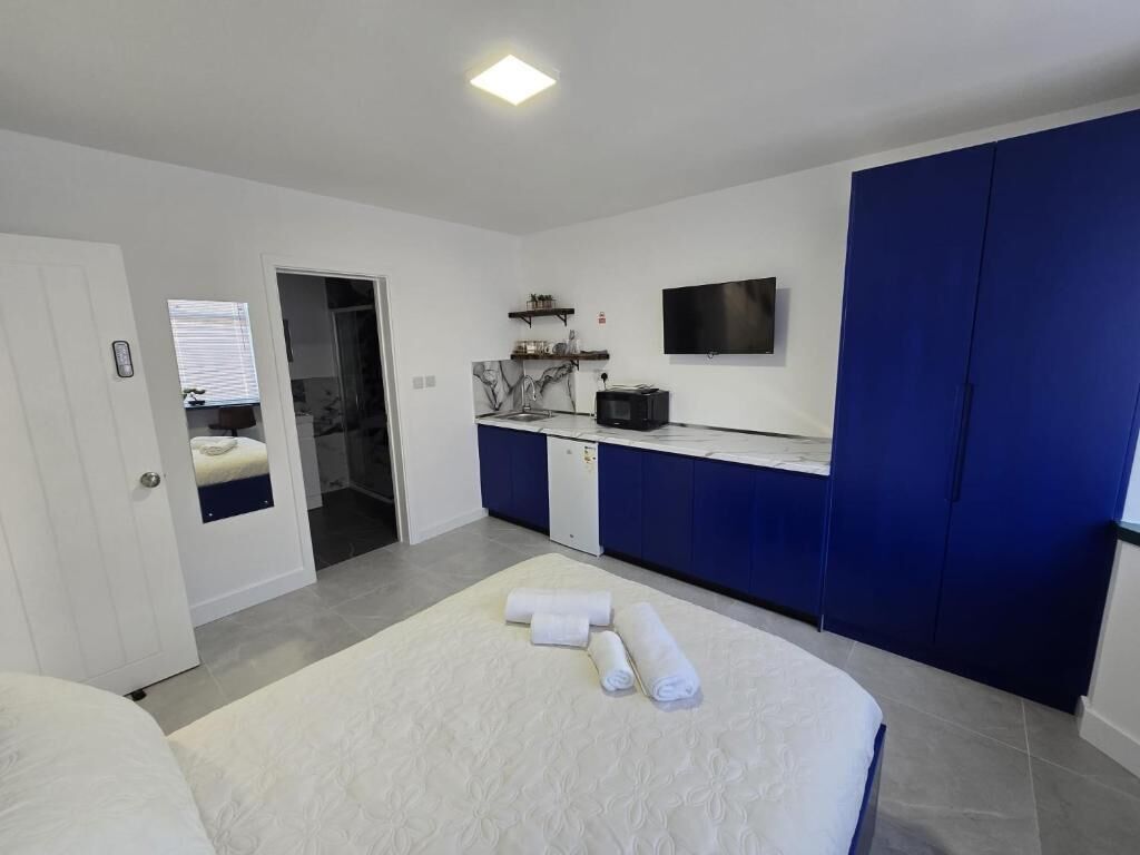 Quarto moderno com cama grande, escrivaninha embutida, televisão de tela plana e closet espaçoso.