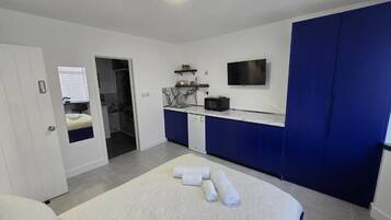Quarto moderno com cama grande, escrivaninha embutida, televisão de tela plana e closet espaçoso.