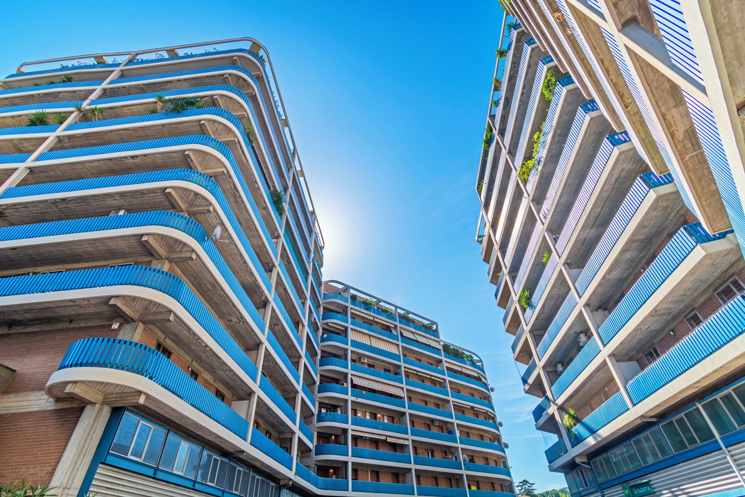 Um edifício com várias andares, varandas, fachada curva e céu claro.