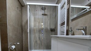 Un bagno moderno con box doccia in vetro, un WC e un lavabo con specchio.