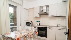Kompakti keittiö, jossa on ruokapöytä, mikroaaltouuni, vedenkeitin, uuni ja kaapit.