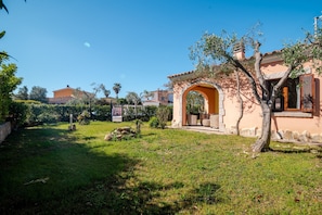 A residential property with a well-maintained lawn, a stone archway, and a house with a tiled roof.