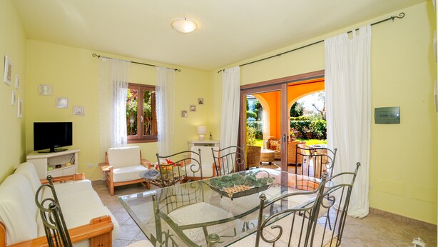 A living room with a glass-top table, chairs, a sofa, a television, and a view of a garden through an open door. - Cottage with Garden in the Center – Private Terrace, Private Garden, Air Conditioning (Suaredda-traversa)
