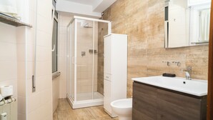 Et moderne badeværelse med brusebad, toilet og håndvask.