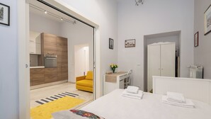 Ein modernes Hotelzimmer mit Bett, Badezimmer, Küchenzeile und einem gelben Sessel.