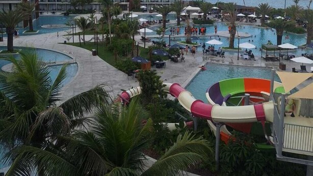 Un resort con varias piscinas, un tobogán de agua y vistas al océano.
