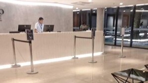 Un vestíbulo moderno con una recepción, divisiones de vidrio y una zona de estar.