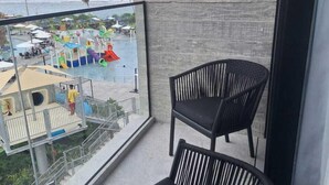 Un balcón con dos sillas negras, vista a un parque acuático y una playa al fondo.