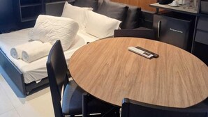Una habitación de hotel moderna con una cama, una mesa redonda de madera, una cafetera y un televisor.