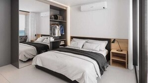 Un dormitorio moderno con dos camas, un vestidor y vistas al océano.