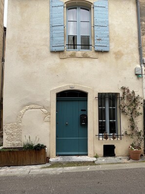 Ein Gebäude mit einer türkisblauen Tür, einem kleinen Fenster mit Fensterläden und einem Schild mit der Nummer 48 über der Tür.