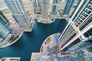 A high-rise building with a marina, modern architecture, and a parking area. - SettlerHomes - Chic JLT 29th Floor - Near Panoramic Lake (Dubai)