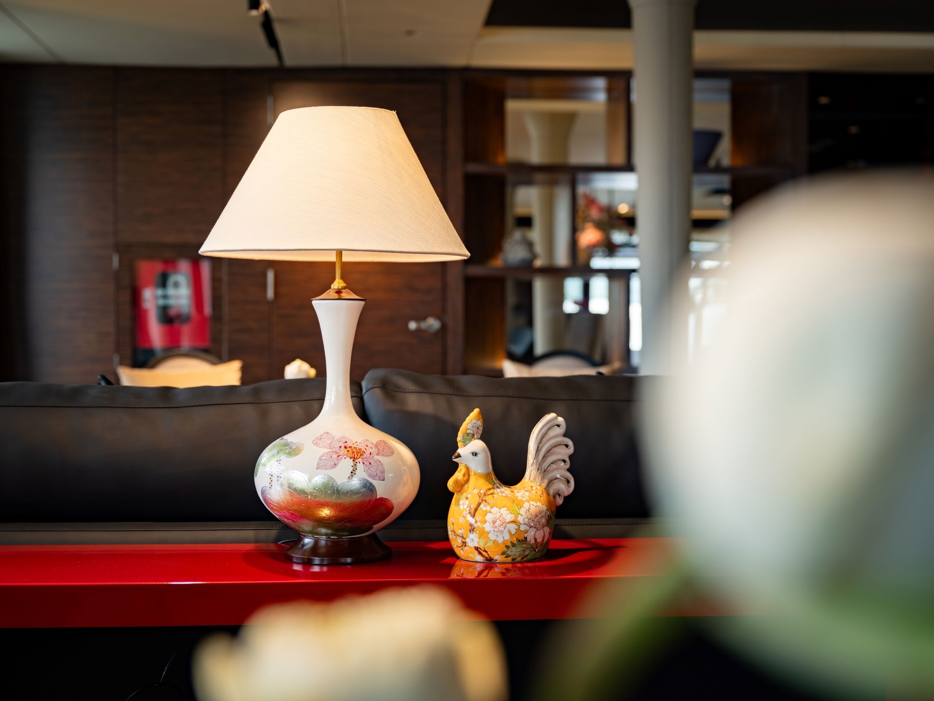 Een tafel met een lamp en een keramieken haan.
