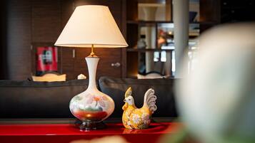 Een tafel met een lamp en een keramieken haan.