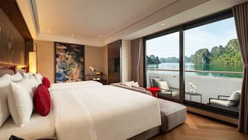 A modern hotel room with a large bed, a balcony with a view of a lake, and a painting on the wall.