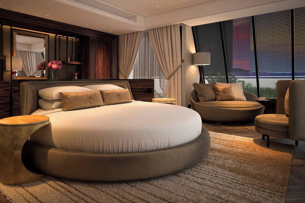 A modern bedroom with a round bed, a sofa, a chair, a nightstand, and a large window with curtains.