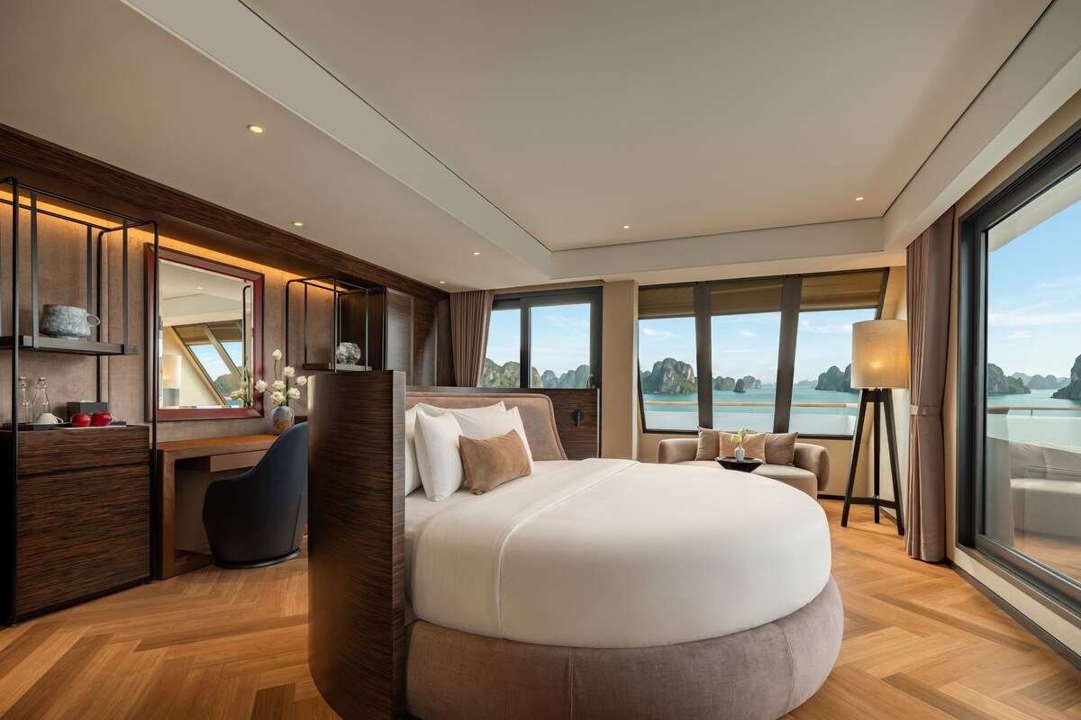 Un dormitorio moderno con una cama grande, un escritorio y vistas al agua.