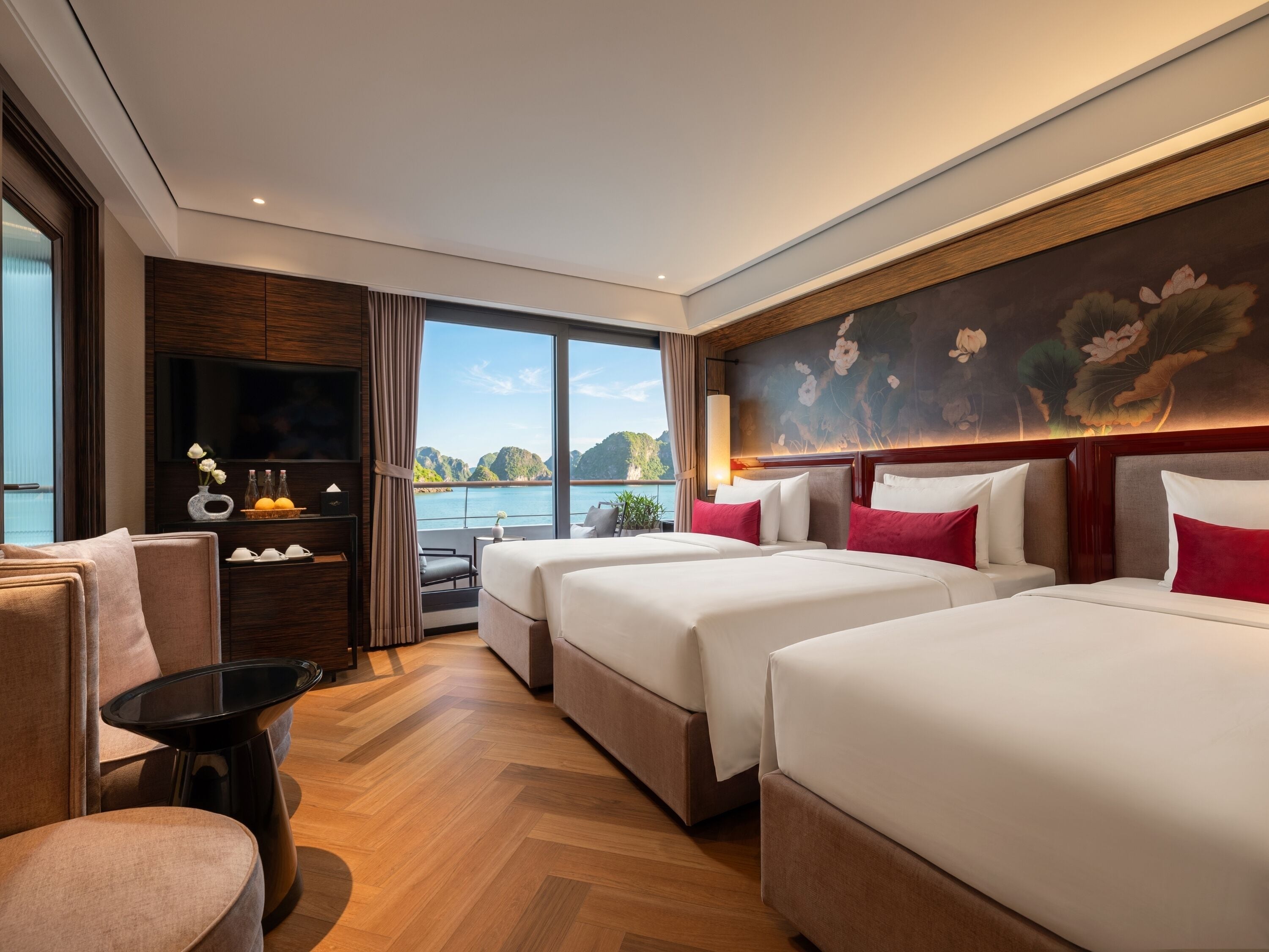 Quarto de hotel com uma janela grande, uma cama, um sofá, uma TV e uma mesinha.