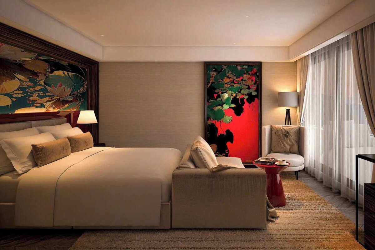A hotel room with a large bed, a sofa, a TV, and a painting on the wall.