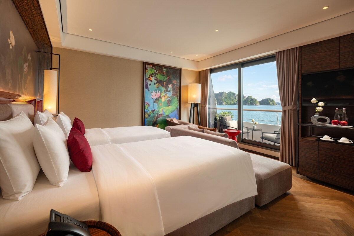 Habitación de hotel con una cama grande, un sofá, televisión y vista a un cuerpo de agua.