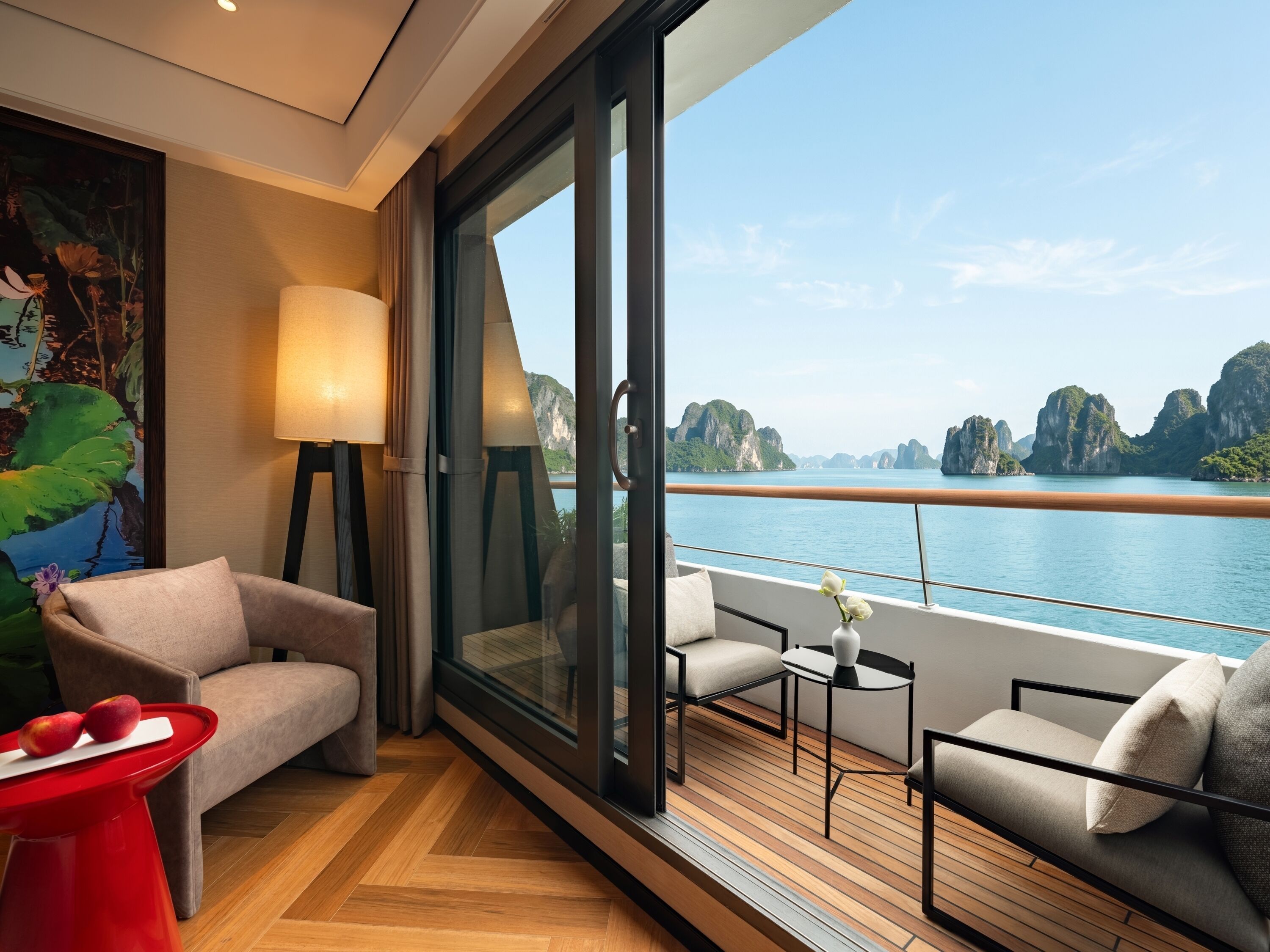 A modern room with a large window, a sofa, a small table, and a red stool.